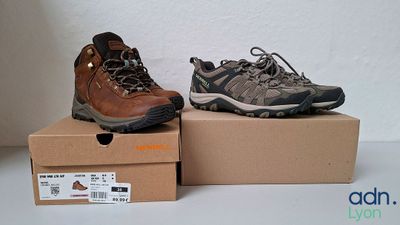 deux paires de chaussures de randonnée posées sur des cartons, sur une table