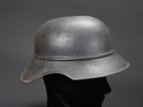 an old steel helmet on a mannequin head on a gray background