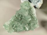 a piece of green crystal on a piece of rock