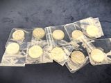several gold coins are in plastic bags on a blue surface