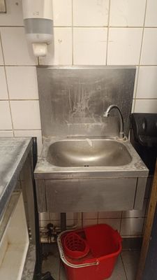 a sink in the corner of a kitchen with a red bucket