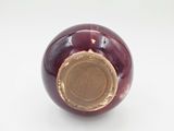 a close up of a red vase with a gold rim