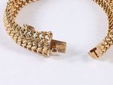 a close up of a gold bracelet on a white surface