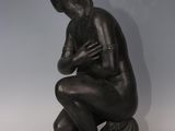 a statue of a man sitting on a rock with his hands crossed