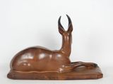 bronze sculpture of a deer laying down on a white surface