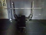 une photo d'une salle de sport avec un banc et une barre