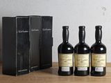 trois bouteilles de vin posées à côté d'une boîte noire sur une table en bois