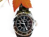 a close up of a wrist watch with a leaf in the background
