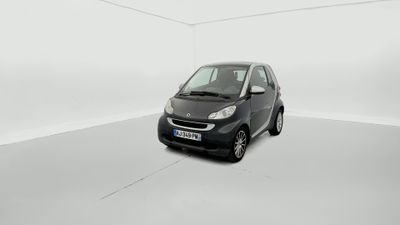 La petite voiture noire est garée dans une pièce blanche.