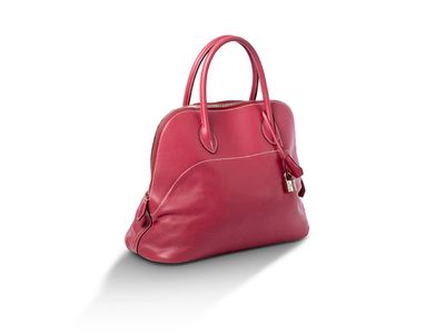 un sac à main rouge posé sur une surface blanche, sur fond blanc