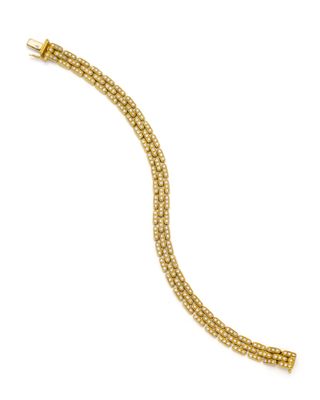 un bracelet en or jaune orné de perles sur fond blanc