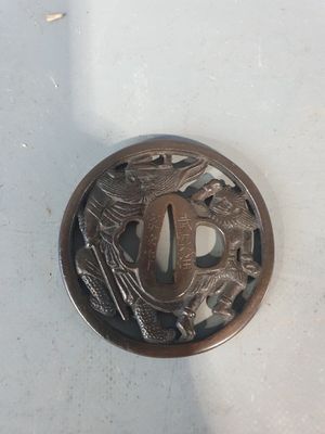 un petit objet en métal orné d'un motif représentant un oiseau