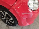 a close up of a red car with a denting on it