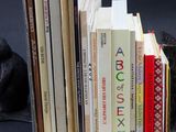 un chat noir assis à côté d'une pile de livres posée sur une table