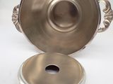 an antique silver plate with a lid on a white surface