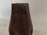 a brown vase sitting on a clear shelf on a table