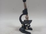 Gros plan sur un microscope posé sur une table, sur fond blanc