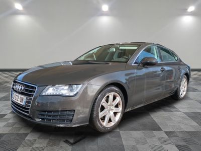 the grey audi is parked on a checkered floor in a garage