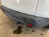 the rear end of a white car with a black bumper