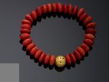 a gold and coral beaded bracelet with a gold ball