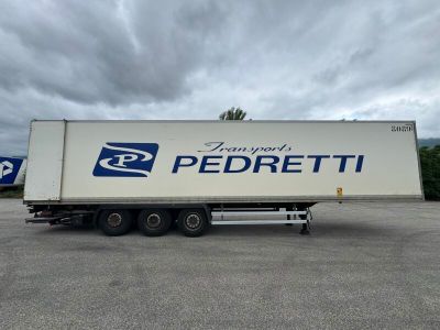 un semi-remorque blanc garé sur un parking sous un ciel nuageux