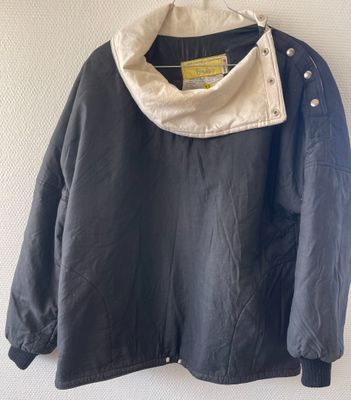 an image of a black jacket hanging on a white wall