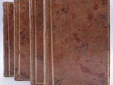 several old books are lined up in a row on a white surface