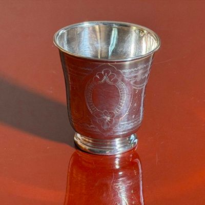 a silver cup sitting on a table with a red background