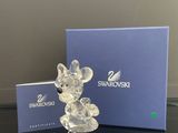 une figurine de Mickey Mouse en verre transparent posée à côté d'une boîte bleue