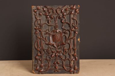 un vieux livre posé sur une table en bois, près d'un mur noir