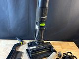 un gros plan d'un aspirateur posé sur une table en bois, à côté d'autres objets