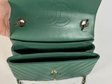 a person holding a green purse with a chain around it