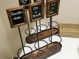 four chalkboards in a holder on a table next to a bowl of fruit