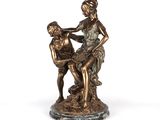 une statue en bronze représentant une femme assise sur les genoux d'un homme