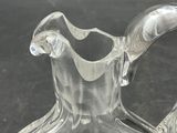 a clear glass pitcher with a curved handle on a table