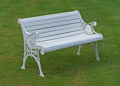 un banc blanc posé au milieu d'un champ herbeux