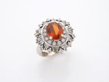 un gros plan d'une bague ornée d'une pierre orange entourée de diamants
