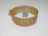 gros plan d'un bracelet en or sur une surface blanche