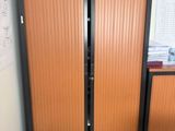 two wooden doors in the corner of a room with papers on the floor