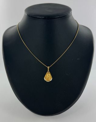 un collier en or avec un pendentif en forme de larme sur un mannequin noir