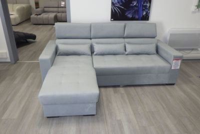 un canapé et un pouf dans un salon où est accroché un tableau au mur