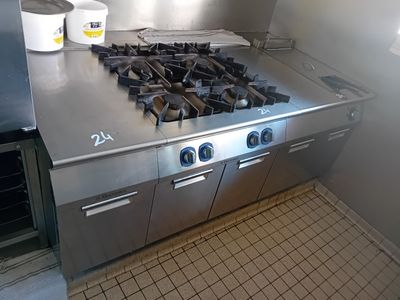 une plaque de cuisson en acier inoxydable dans une cuisine où se trouve un seau sur le plan de travail