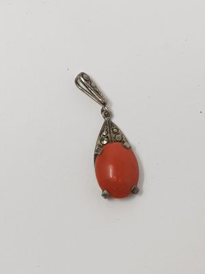 an orange coral pendant with a silver bail