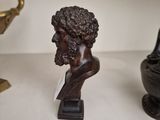 a bust of a man on a table next to a vase
