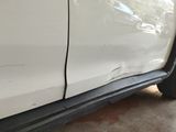 the side of a white car with a dent in the side of it