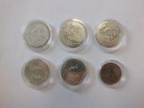 six different types of coins in plastic containers on a white surface