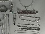 a lot of silver jewelry on a white surface