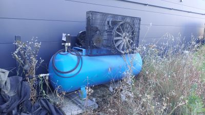 a blue tank with a fan attached to it next to a building