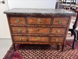 a wooden chest of drawers with marble top on a rug