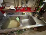 a sink in the middle of a kitchen with pots and pans hanging on the wall